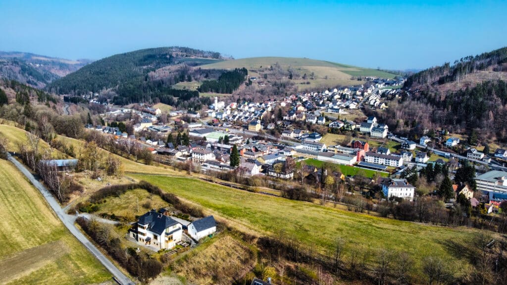 Eine hügelige Landschaft mit überwiegenden Einfamilienhäusern an einem sonnigen Tag